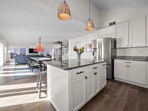 A modern kitchen with white cabinetry, a granite countertop, and stainless steel appliances. - Dog-friendly 5BR Beach Home with Pool & Ocean Views (Emerald Isle)