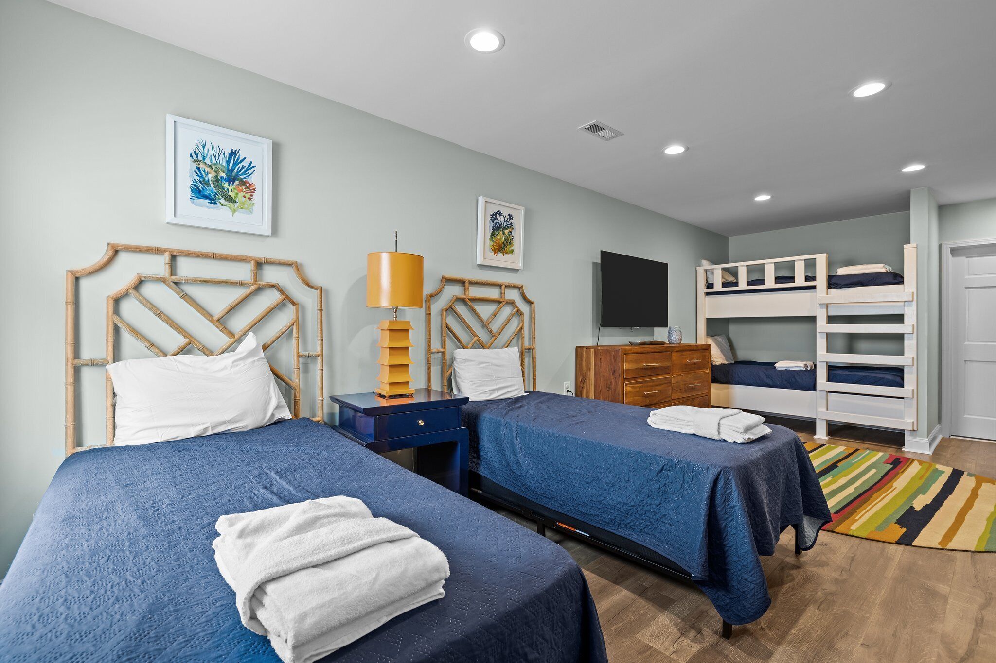 Een slaapkamer met twee bedden, een televisie, een dressoir en een stapelbed.