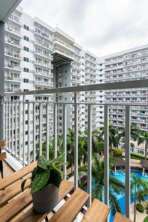 Ein Balkon mit Blick auf hohe Gebäude, einen Pool und einen Blumentopf.