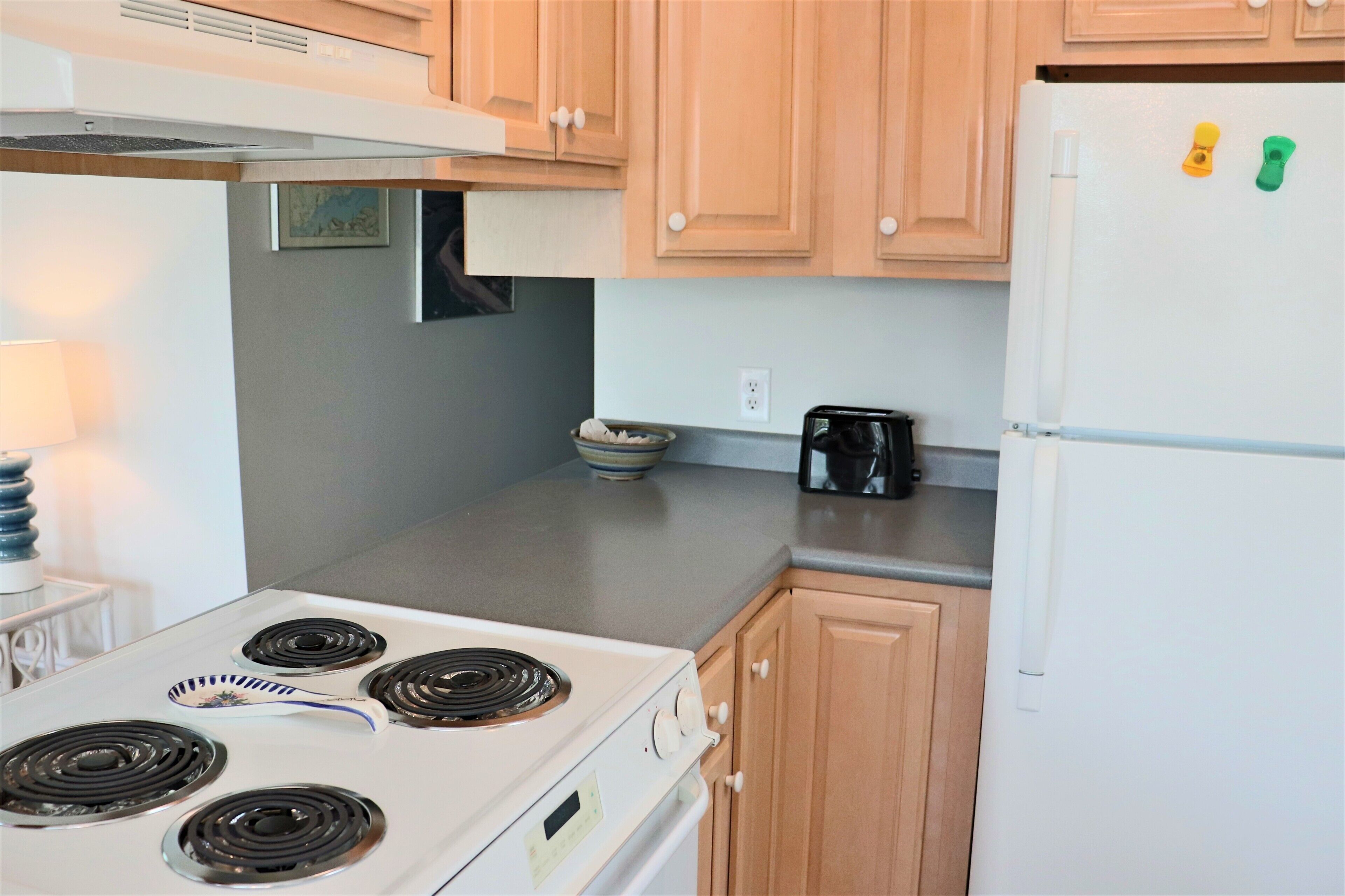 A kitchen with a stove, a coffee maker, and wooden cabinets.