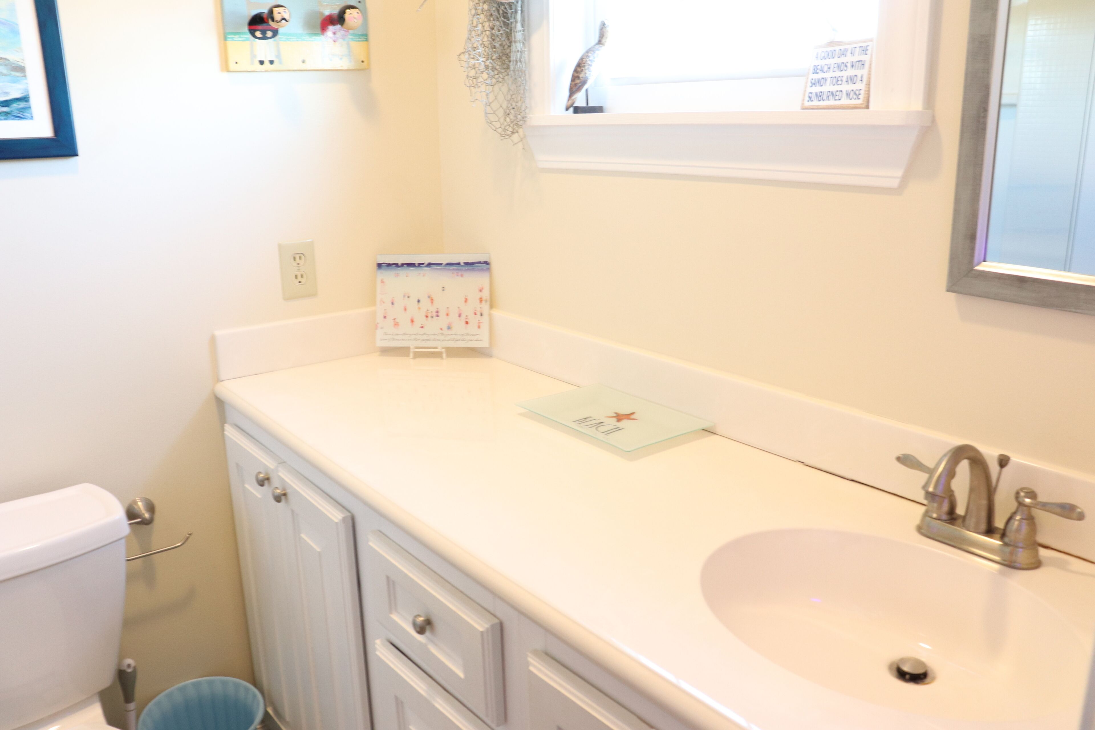 Une salle de bain avec un lavabo blanc, des toilettes et un meuble de rangement.