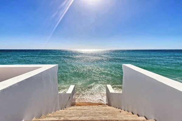 A staircase leading to a beach with a clear sky and calm sea. - Casa del Espíritu | 8BR Beachfront | Sleeps 16 (Puerto Peñasco)