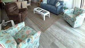 Ein Wohnzimmer mit einer Couch, zwei Sesseln, einem Couchtisch und einem Essbereich mit Stühlen und einem Tisch.