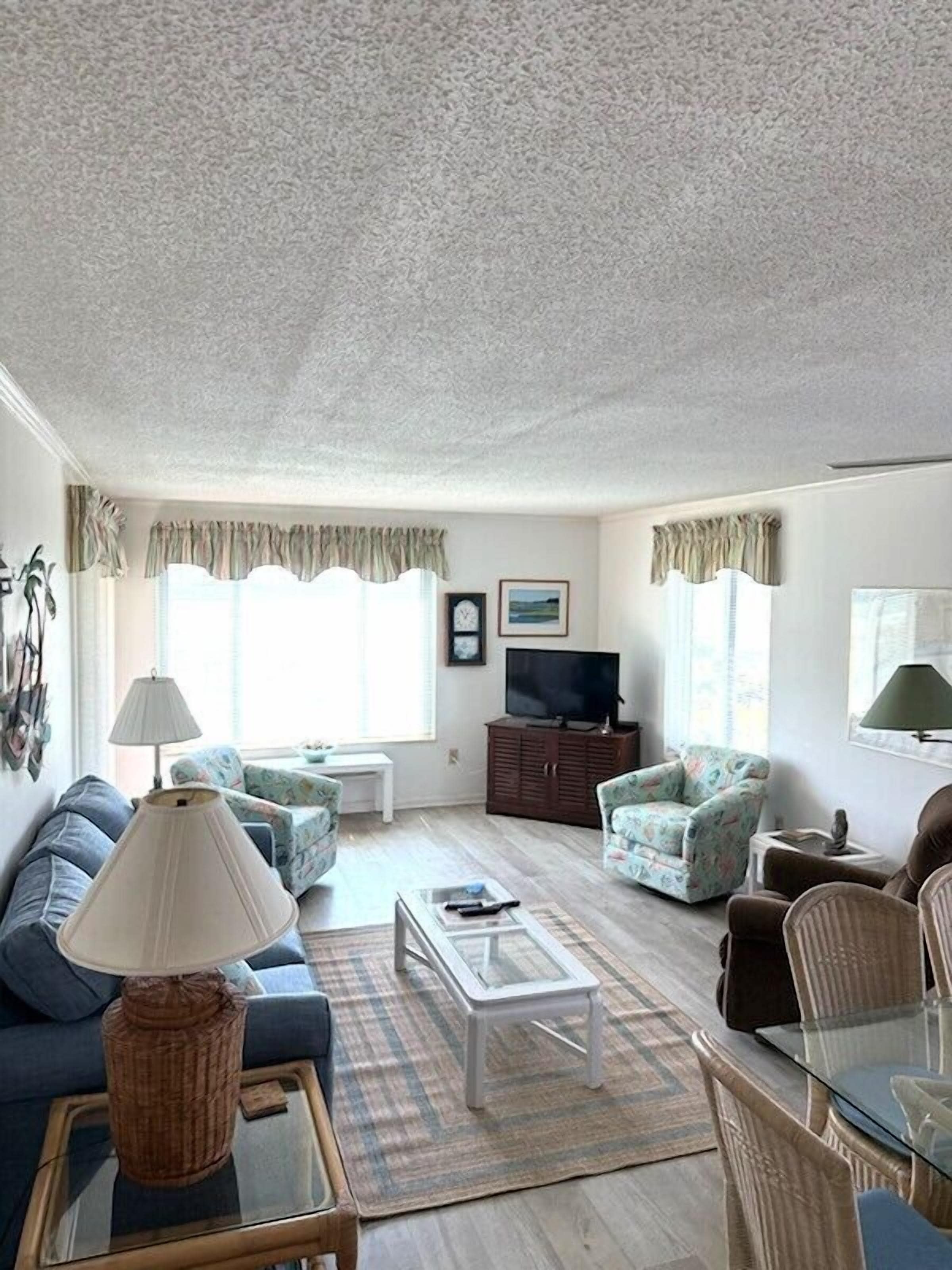 A living room with a sofa, armchairs, a coffee table, a television, and a cabinet.