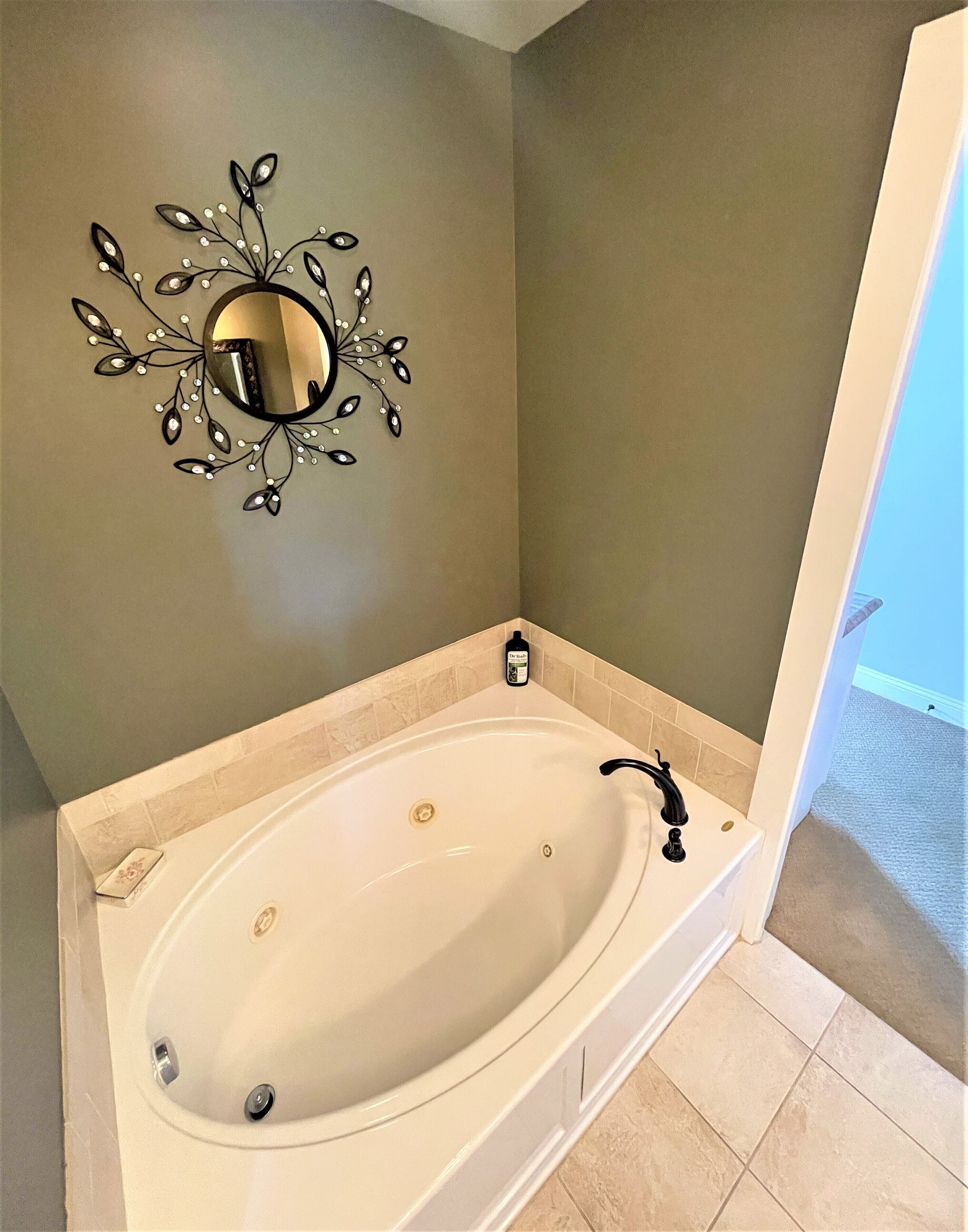 Une salle de bain avec une baignoire sur pieds, un miroir fixé au mur et un petit flacon de savon liquide posé sur le bord.