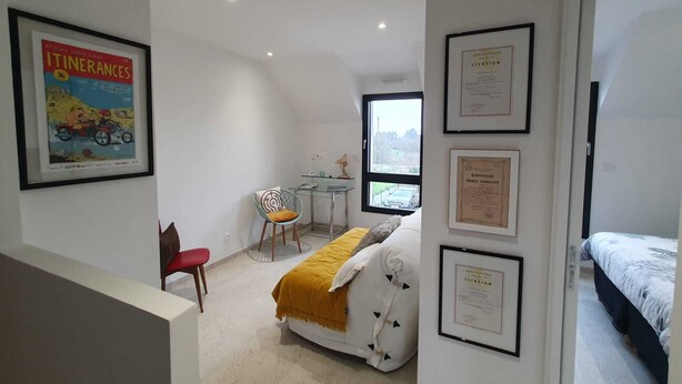 Un dormitorio con una cama, un escritorio y una silla. Hay diplomas enmarcados en la pared.