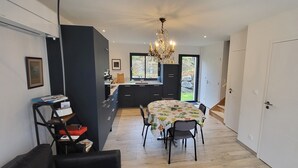 Una cocina moderna con armarios oscuros, una mesa de comedor con sillas y una araña.