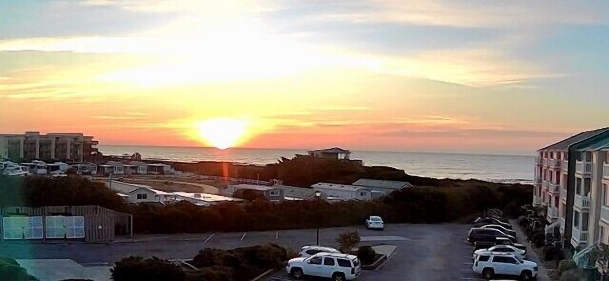 Vista sulla costa con il tramonto, parcheggi e edifici.
