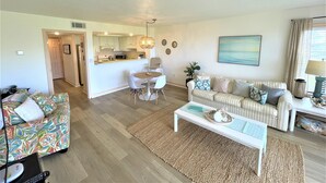 A modern living room with a sofa, a coffee table, and a dining area with a table and chairs.