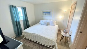 A bedroom with a bed, a bedside table, a lamp, and a window with curtains.