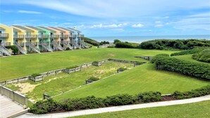 A coastal hotel with colorful buildings, a grassy lawn, and a view of the ocean.
