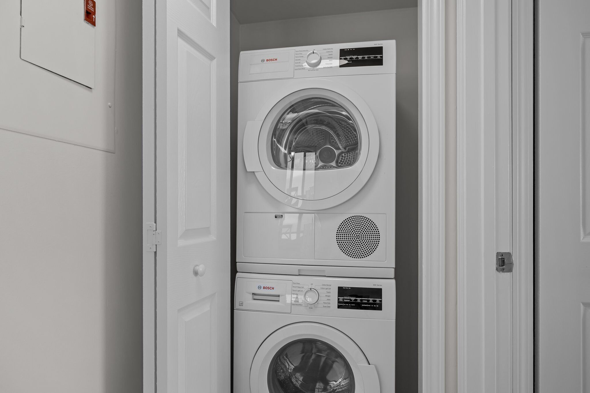 A stacked washer and dryer unit in a hallway.