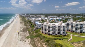 Et kysthotel med flere etager, udsigt til stranden og parkeringsplads.