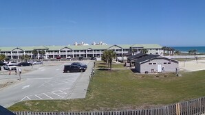 A coastal hotel with multiple buildings, a parking lot, and a view of the ocean. - Your Slice of Oceanfront Paradise at Queens Court (Emerald Isle)