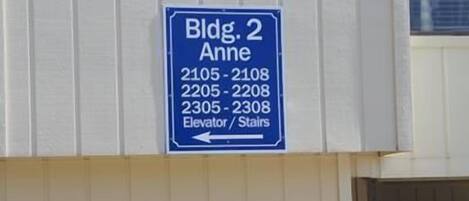 A directional sign for Bldg. 2 Anne with room numbers 2105-2108, 2205-2208, and 2305-2308, indicating elevator/stair access.