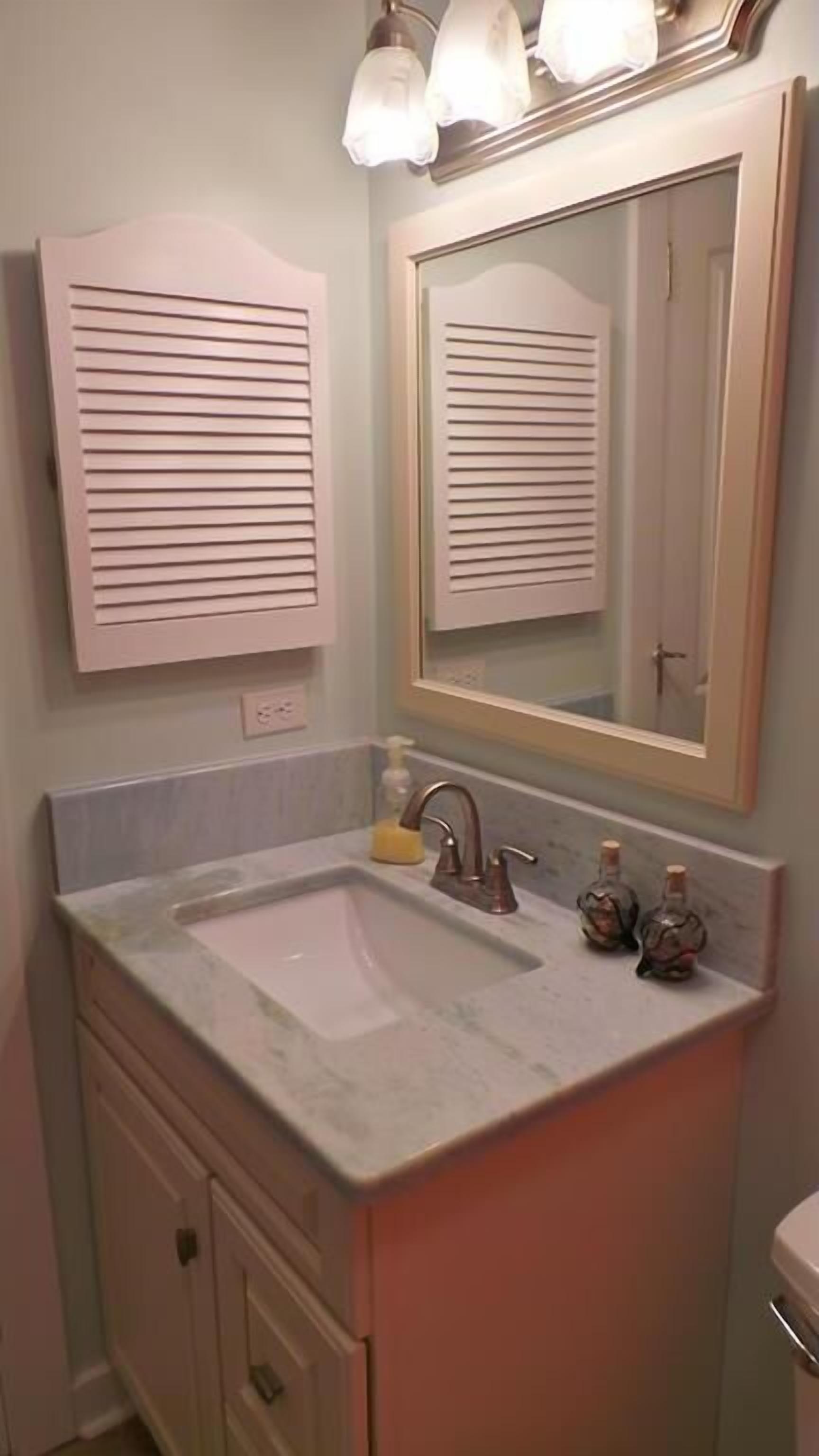 Une salle de bain avec un lavabo, un miroir et des placards.