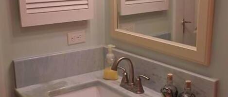 Une salle de bain avec un lavabo, un miroir et des placards.