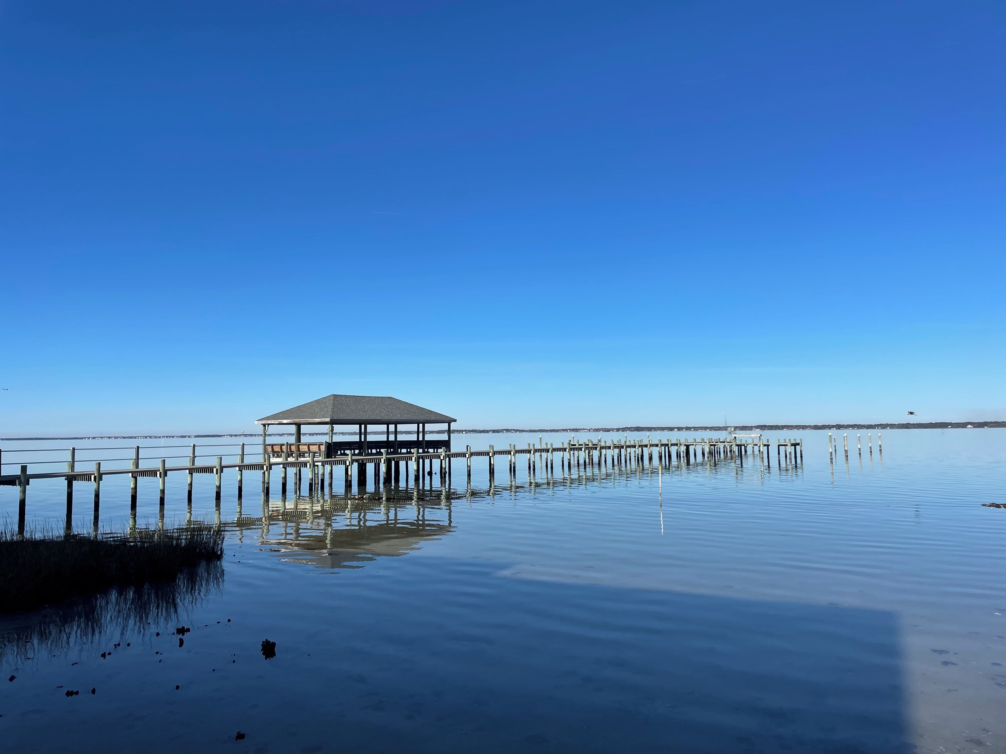 A pier extending into calm water with a covered structure at the end.