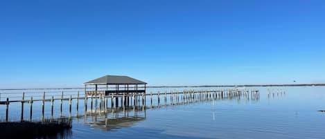 A pier extending into calm water with a covered structure at the end.
