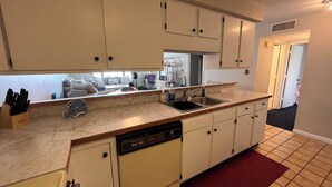 A compact kitchen with white cabinets, a dishwasher, and a sink.