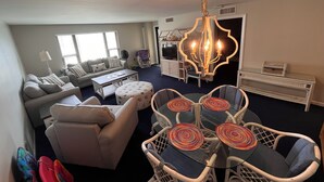 A living room with a sofa, coffee table, and a dining area with chairs and a chandelier.