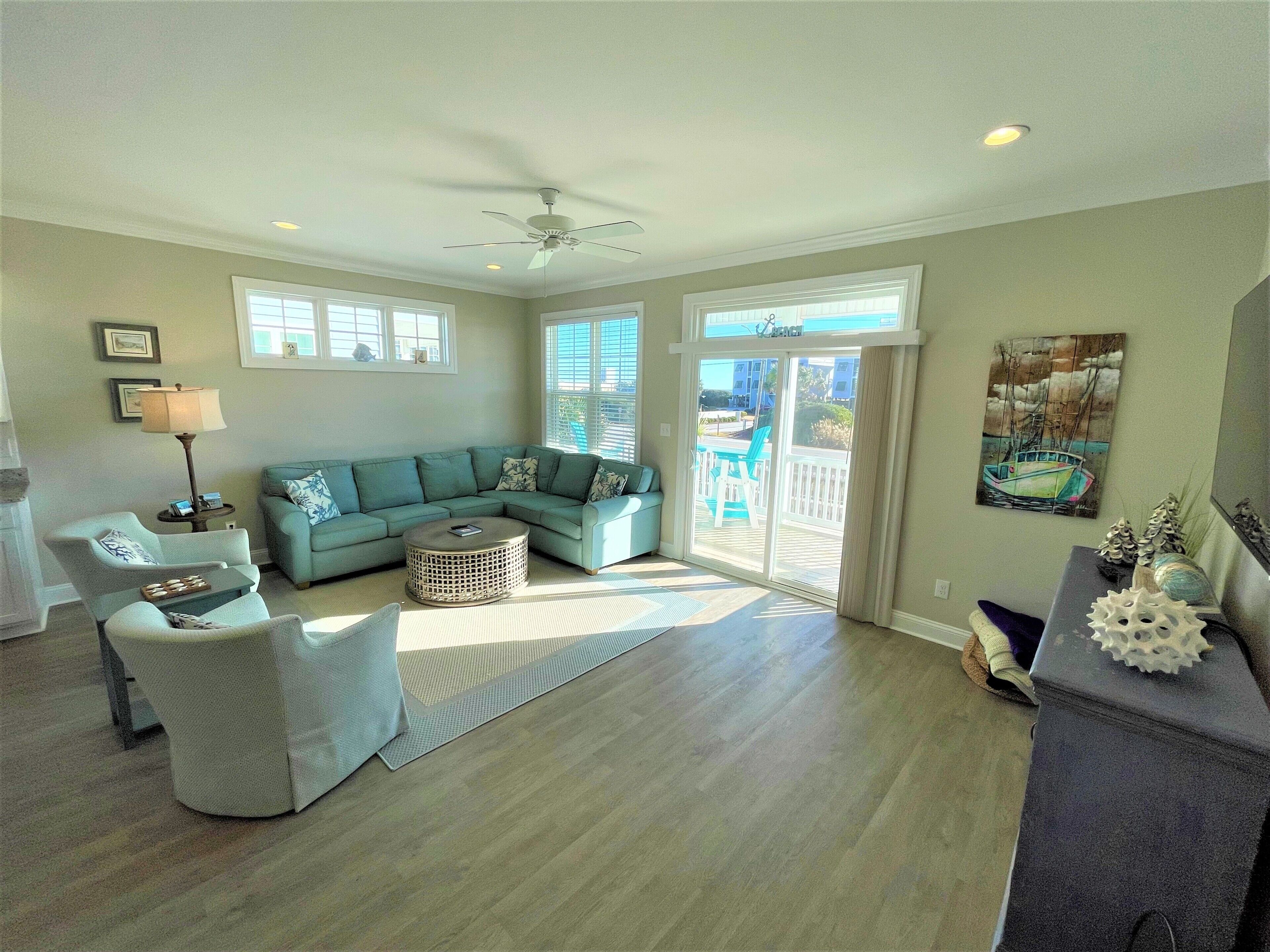 A spacious living room with a sectional sofa, a round coffee table, and a ceiling fan.