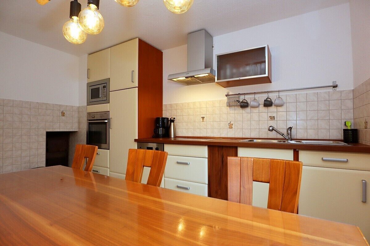 A compact kitchen with a wooden dining table, white cabinets, and a microwave.