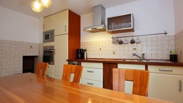 A compact kitchen with a wooden dining table, white cabinets, and a microwave.