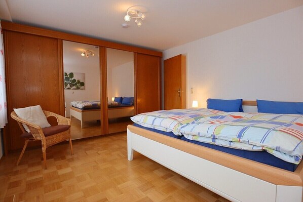 A bedroom with a bed, a chair, and a wardrobe. - Erdgeschoßwohnung 85qm (Villingen-Schwenningen)