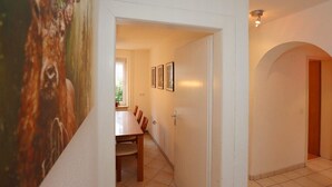 A hallway with a dining area, a door leading to another room, and a wall with a framed picture. - Erdgeschoßwohnung 85qm (Villingen-Schwenningen)
