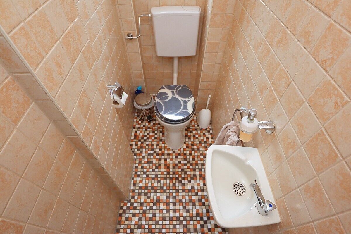 A bathroom with a toilet, sink, and tiled floor.