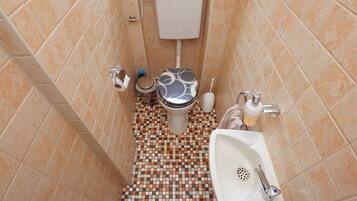 A bathroom with a toilet, sink, and tiled floor.