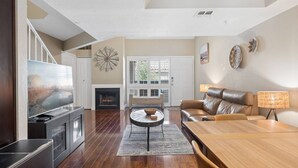 Una sala de estar con chimenea, televisor, sofá y mesa de centro.