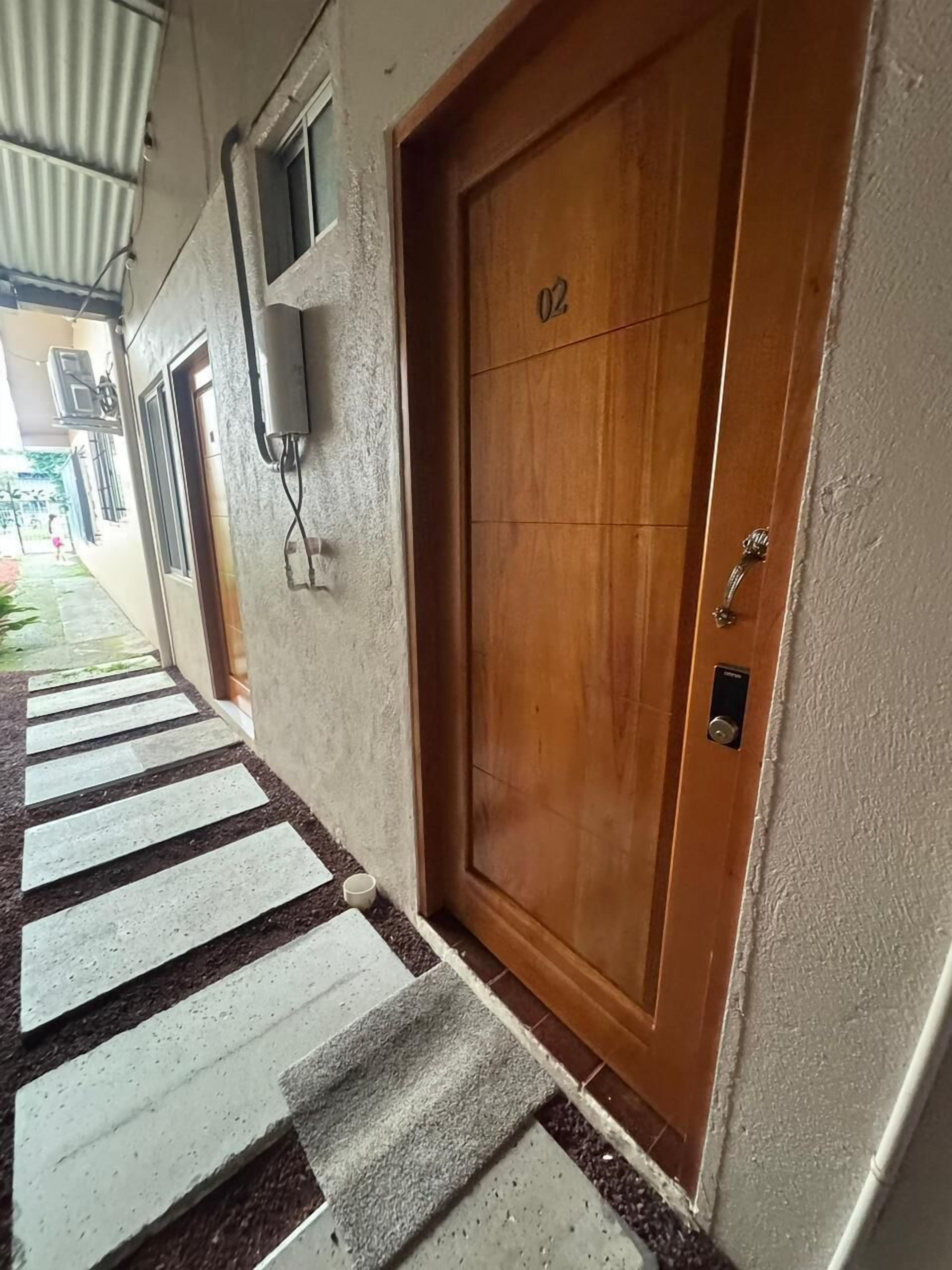 A wooden door with the number 02, a small window, and a wall-mounted air conditioning unit.