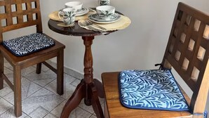 Un pequeño comedor con dos sillas de madera, una mesa redonda y un televisor de pantalla plana montado en la pared.