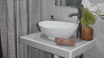 Een badkamer met een witte wastafel, een spiegel, een handdoek, een kamerplant en een douchegordijn.