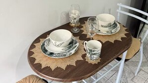 A round dining table with a brown tablecloth, white plates, and a glass. - Cozy Stay in La Fortuna with Parking, WiFi & Smart TV #4 (La Fortuna)