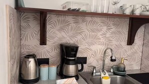 A kitchen with a coffee maker, kettle, and a sink with a soap dispenser. - Cozy Stay in La Fortuna with Parking, WiFi & Smart TV #4 (La Fortuna)