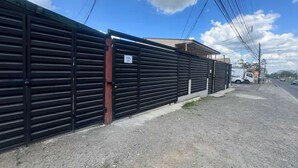 A gated property with a gravel driveway and a building in the background. - Cozy Stay in La Fortuna with Parking, WiFi & Smart TV #4 (La Fortuna)