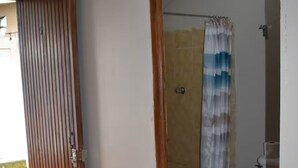 Un bagno con doccia, toilette e una porta che dà su uno spazio all'aperto.