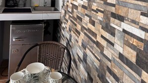 Ett kök med modern design, med en stänkskyddsplatta som efterliknar sten, en inbyggd diskmaskin och ett kylskåp i rostfritt stål.