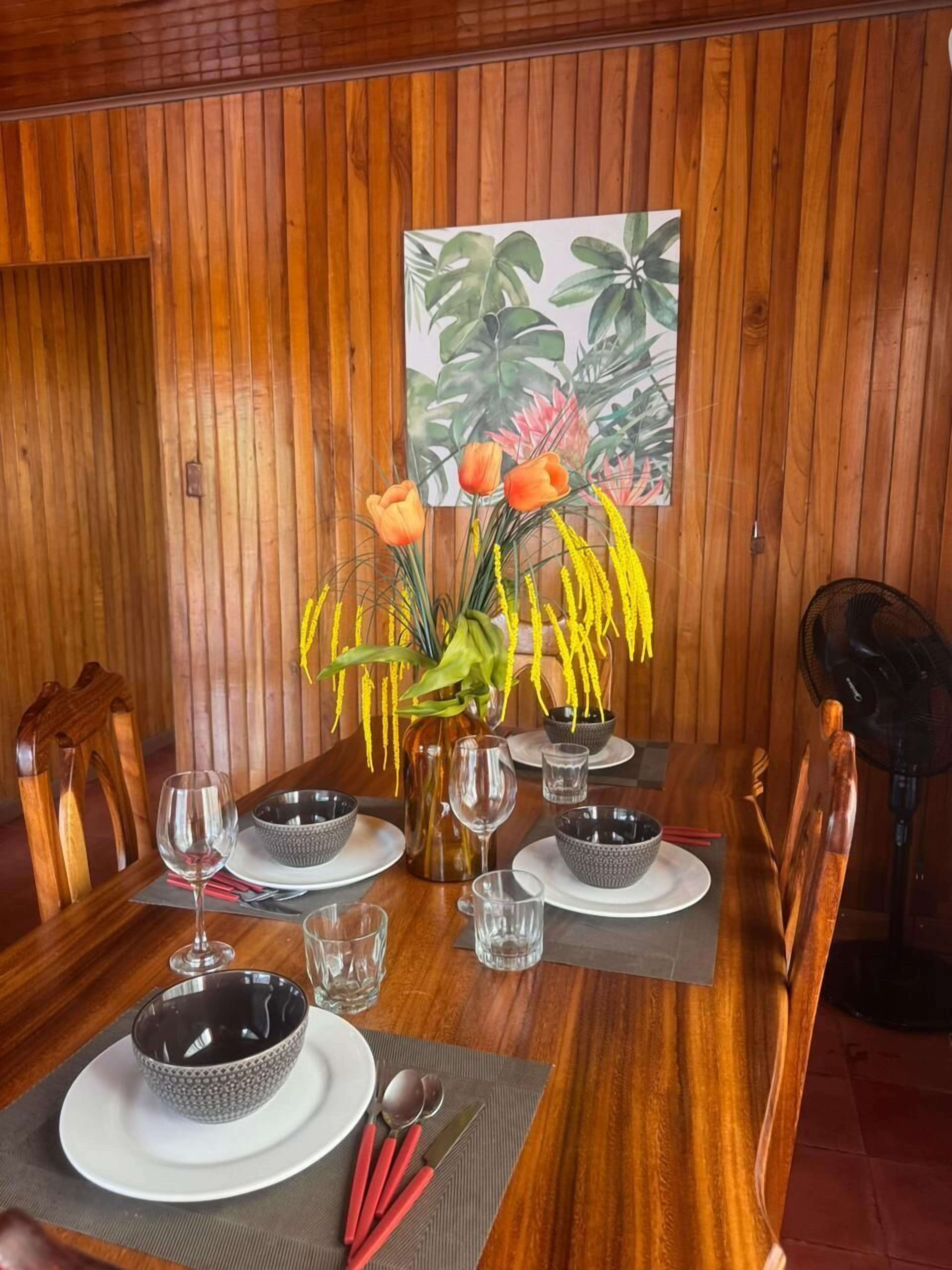 Un tavolo da pranzo in legno apparecchiato con piatti, ciotole, bicchieri e posate.