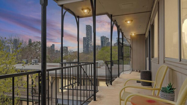 A balcony with a city view, a chair, a small table, and a potted plant. - Stylish 1BR/1BA SoCo Condo | Skyline Views, Pool & Parking by Austin Vacay (Austin)