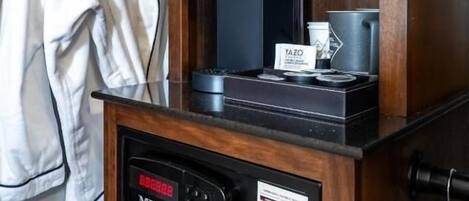 A coffee machine, a TAZO cup, and a digital control panel on a wooden shelf.