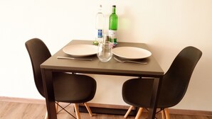 A dining table with two chairs, two plates, a fork, a knife, a glass, and two bottles. - Room 116 at the AlbThermen (Bad Urach)