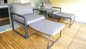 A sunlit outdoor seating area with metal-framed chairs and a table, featuring a view of greenery through a window. - Room 116 at the AlbThermen (Bad Urach)