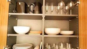 A kitchen cabinet with shelves containing various kitchenware, including plates, bowls, cups, and a kettle. - Room 116 at the AlbThermen (Bad Urach)