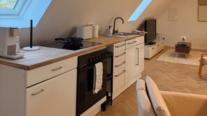 Ett modernt kök med ett takfönster, en inbyggd ugn och en matplats med en stol.