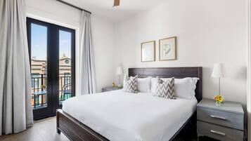 A hotel room with a large bed, two bedside tables, a ceiling fan, and a view of the outside.