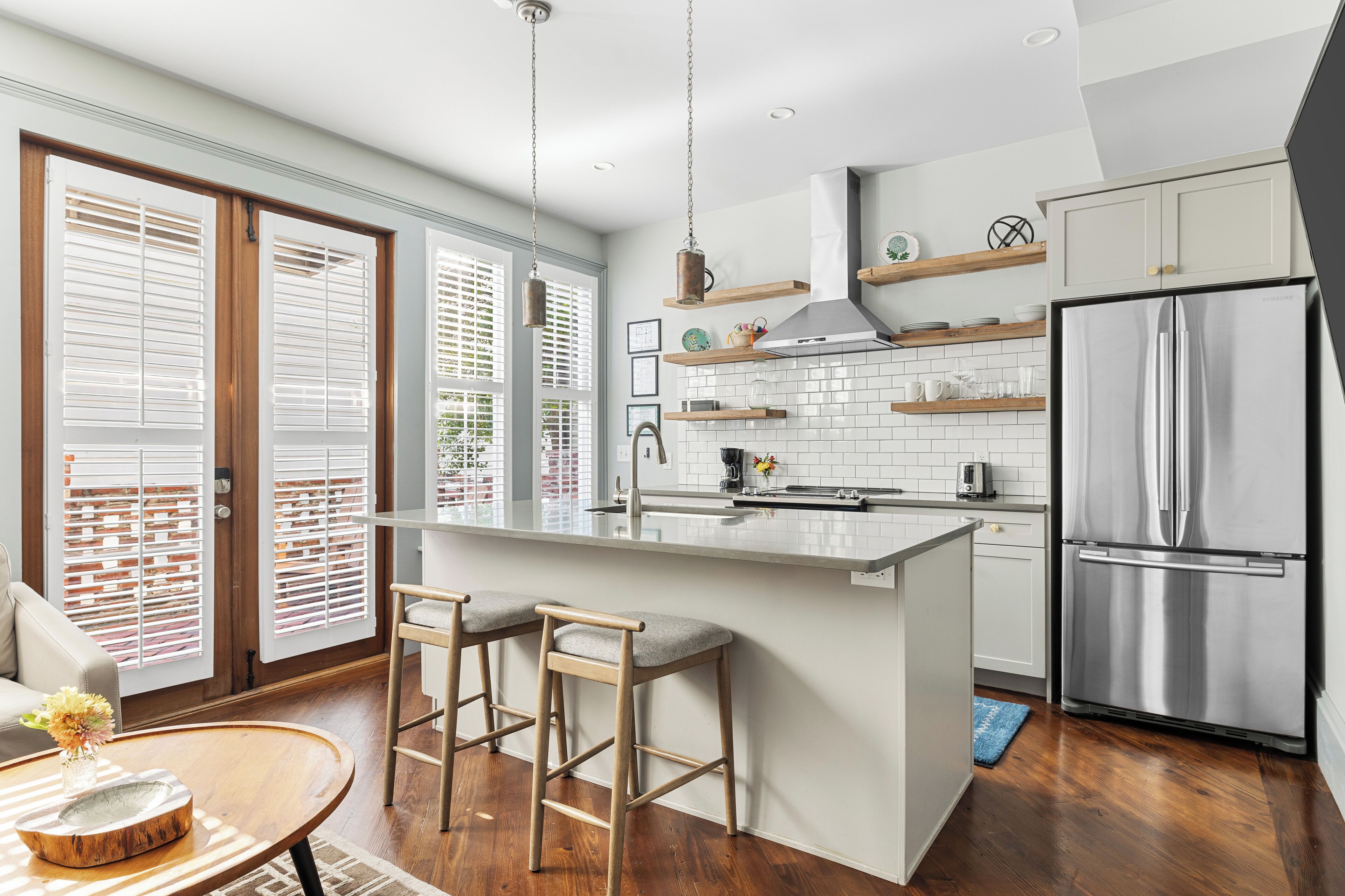 A modern kitchen with a large island, stainless steel appliances, and a dining area with bar stools.